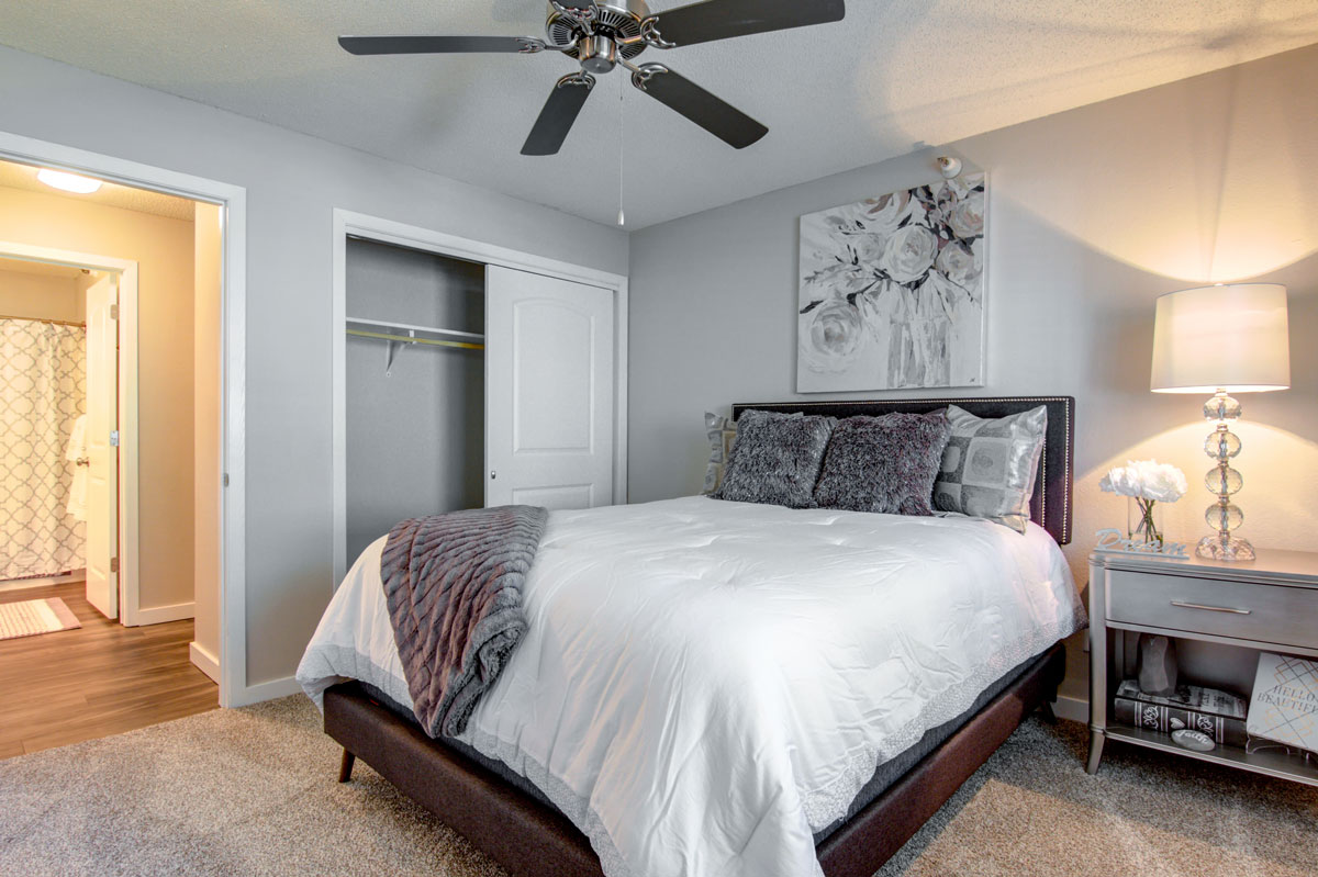 Colonial Estates bedroom with a queen bed and closet with grey and white decor.